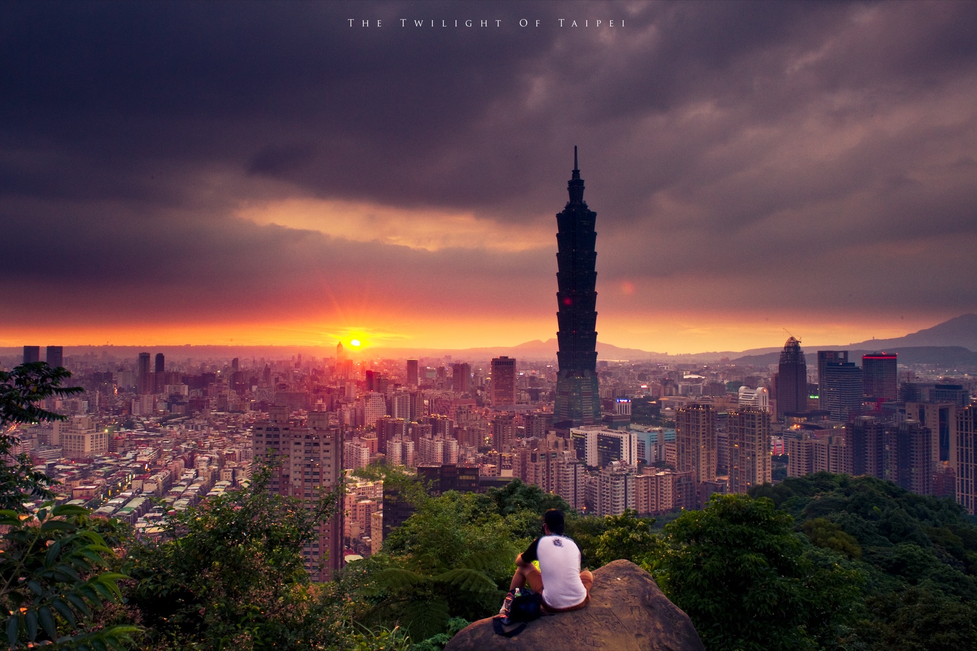 Taipei 101 skyline at dusk surrounded by green mountains